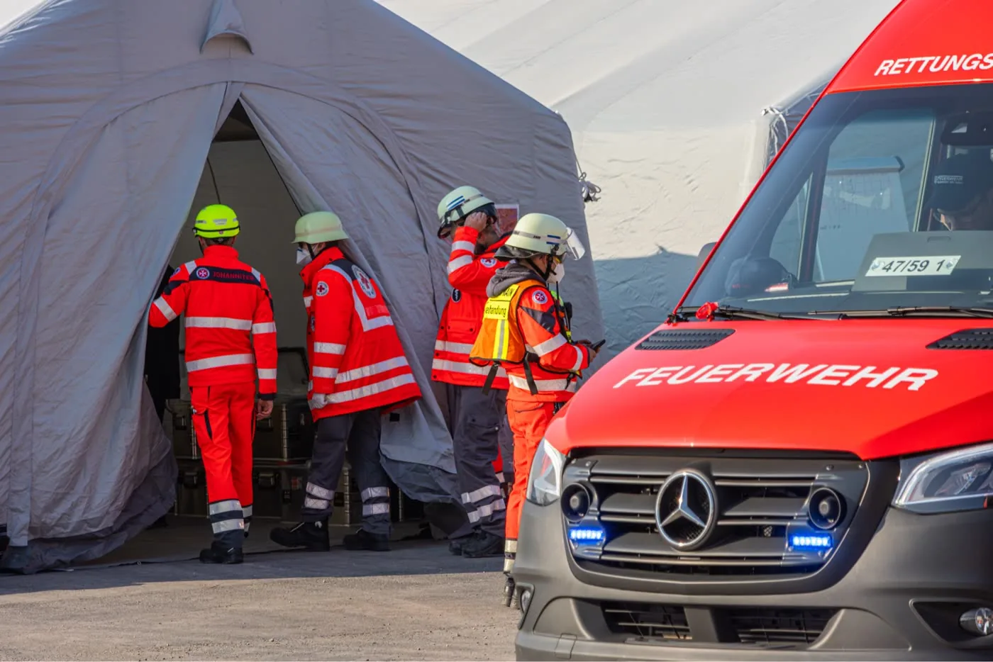 Behandlungsplatz bei einer Katastrophenschutzübung: Einsatzkräfte von Johannitern und DRK am Zelt, davor ein Rettungswagen der Feuerwehr