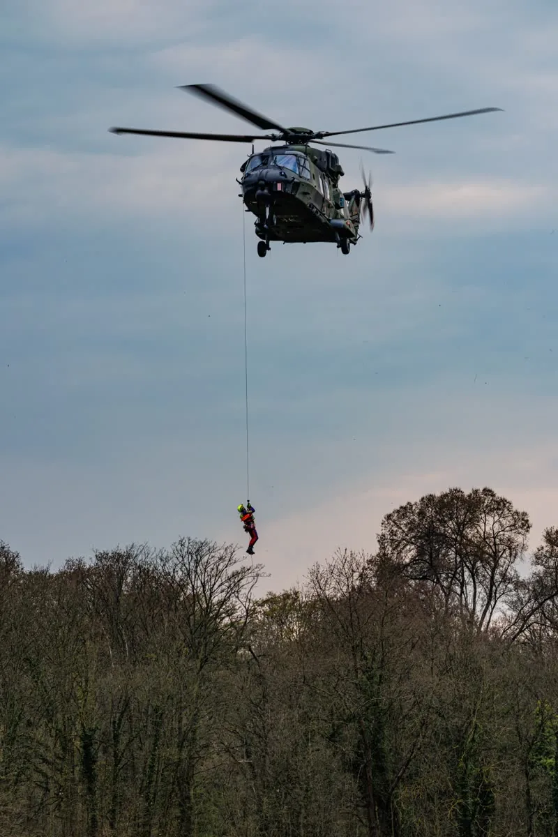 Windenrettung bei einer Übung: Ein Luftretter wird an der Winde eines NH90-Hubschraubers der Bundeswehr über einem Waldstück abgelassen